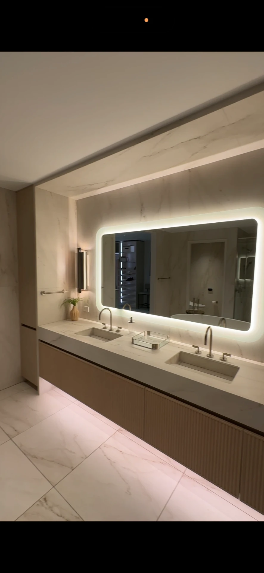 Primary bathroom with backlit mirror, double vanity, and marble-look porcelain surfaces inside a residence at The Ritz-Carlton Residences, Estero Bay