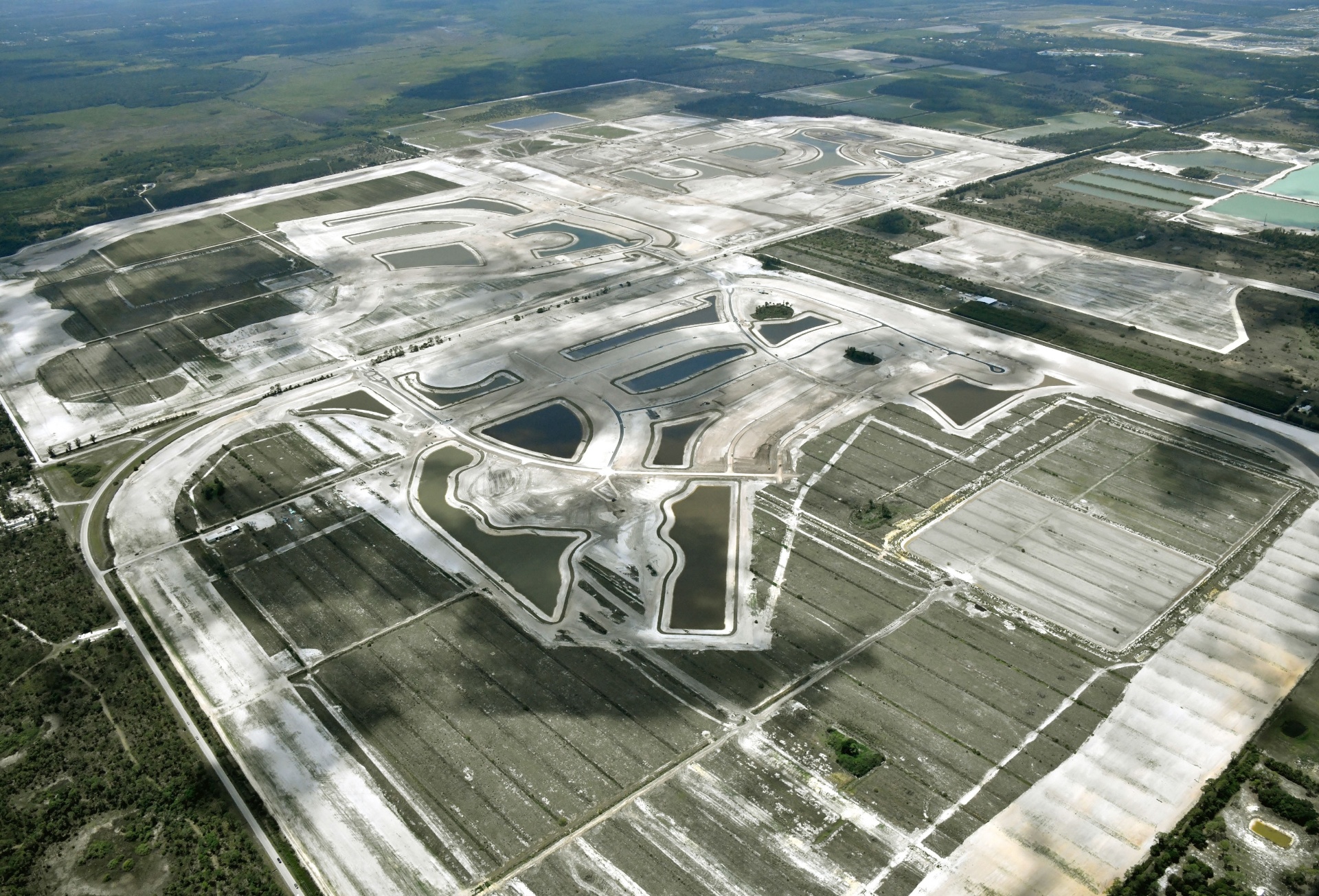 Aerial photo of Kingston site development in Estero, Florida — graded home sites, lake excavation and new roadways with Southwest Florida International Airport in the distance