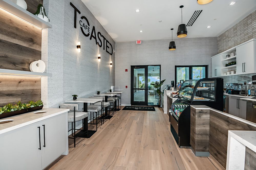 Toasted Cafe interior at an Esplanade amenity center with coffee bar, pastry case, and cafe tables, representative of the cafe planned for Esplanade at Kingston