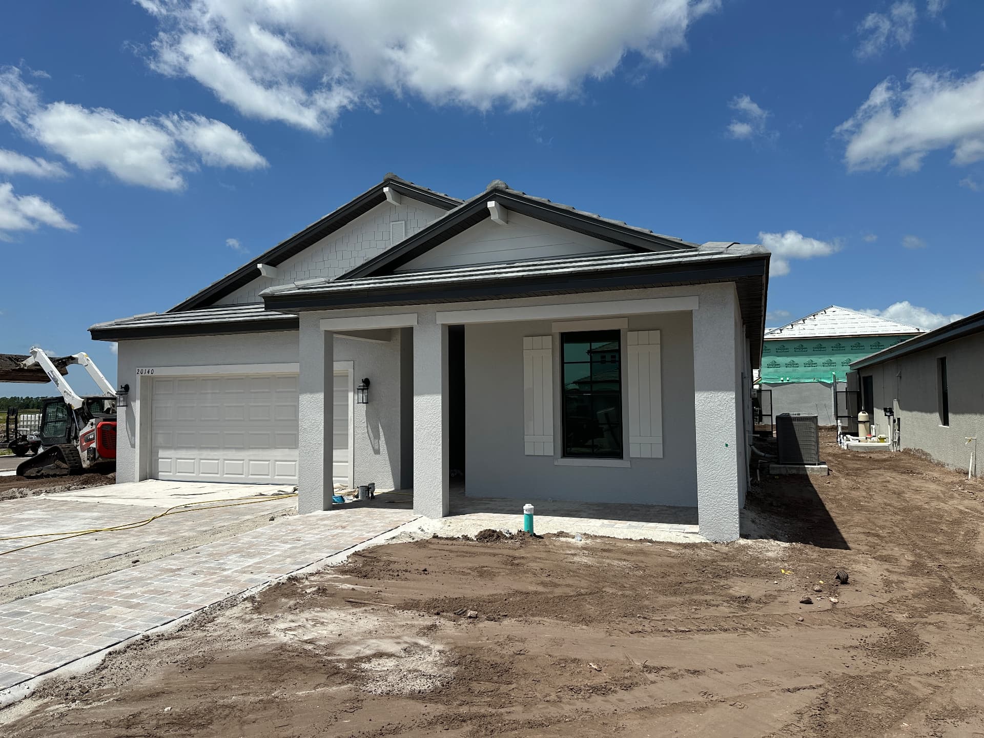 Front elevation of a new construction single-story home under finishing work in Kingston, Estero, Florida — August 2026