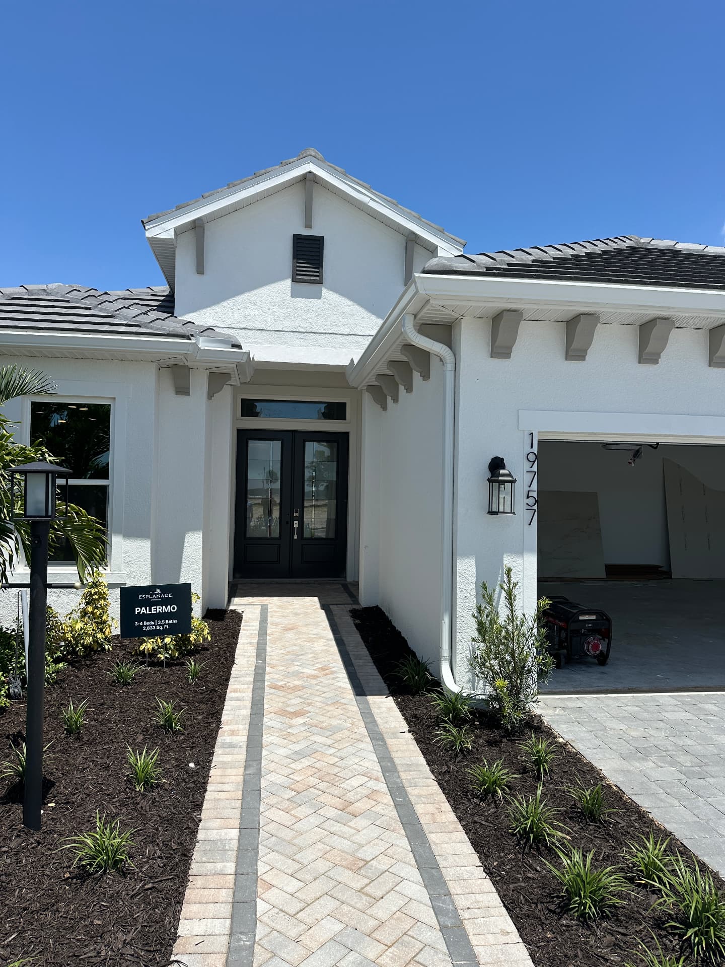 Esplanade at Kingston model home front entry with herringbone paver walkway in Estero, Florida — August 2026