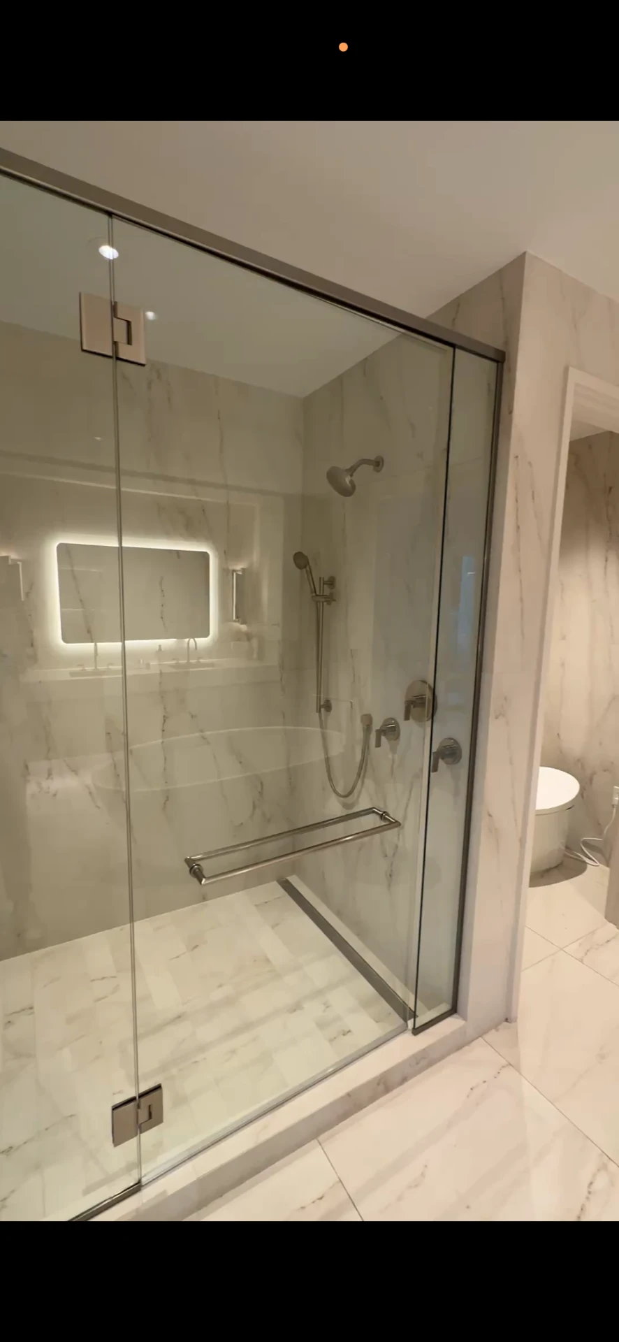 Frameless glass walk-in shower with bench and soaking tub in a primary bathroom at The Ritz-Carlton Residences, Estero Bay