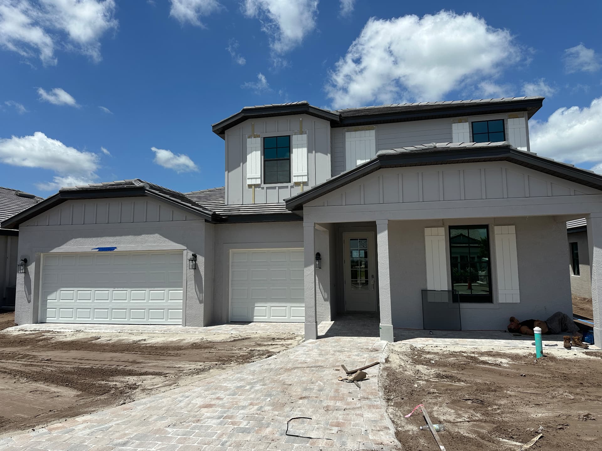 Two-story new construction home with three-car garage mid-finish in Kingston, Estero, Florida — August 2026