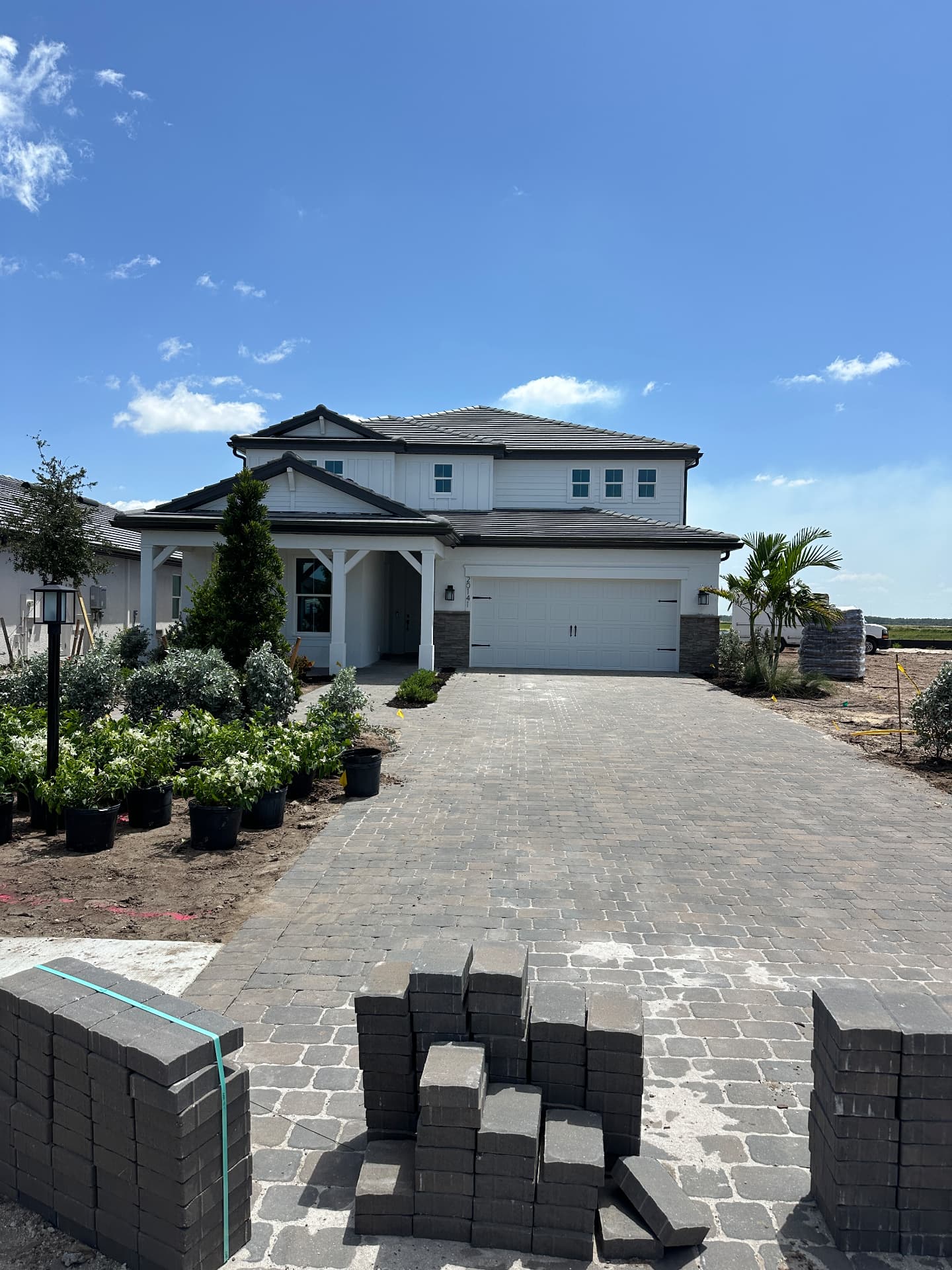 Two-story new construction home with paver driveway and fresh landscaping in Kingston, Estero, Florida — August 2026