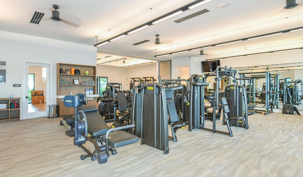Esplanade fitness center with strength machines, cardio equipment, and mirrored walls, representative of the state-of-the-art fitness center planned for Esplanade at Kingston