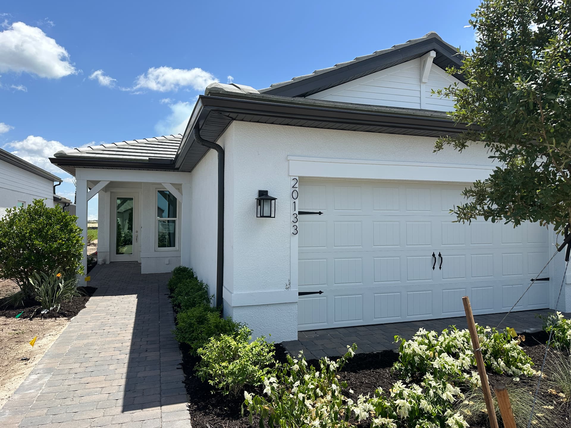 Completed new construction home with mature landscaping and paver walkway in Kingston, Estero, Florida — August 2026